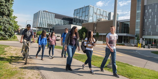 Students walk and cycle across a sunny University of Waterloo campus.