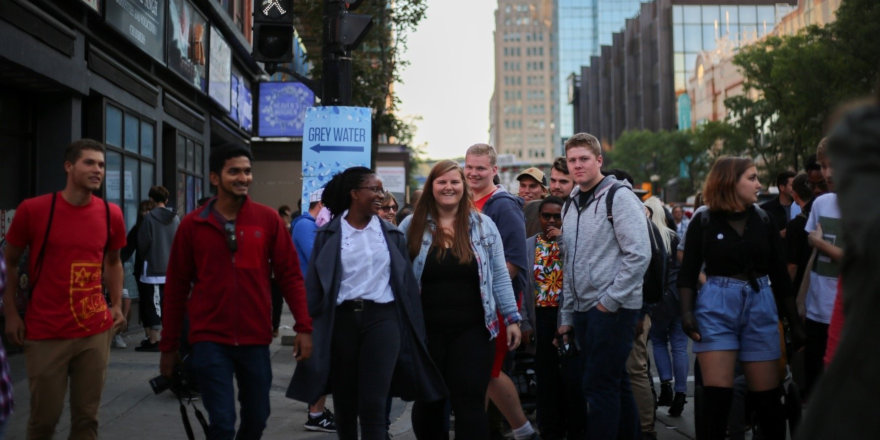 A group of cheerful students makes their way through a busy city street.