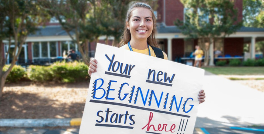 A smiling girl holds a poster reading Your New Beginning Starts Here!