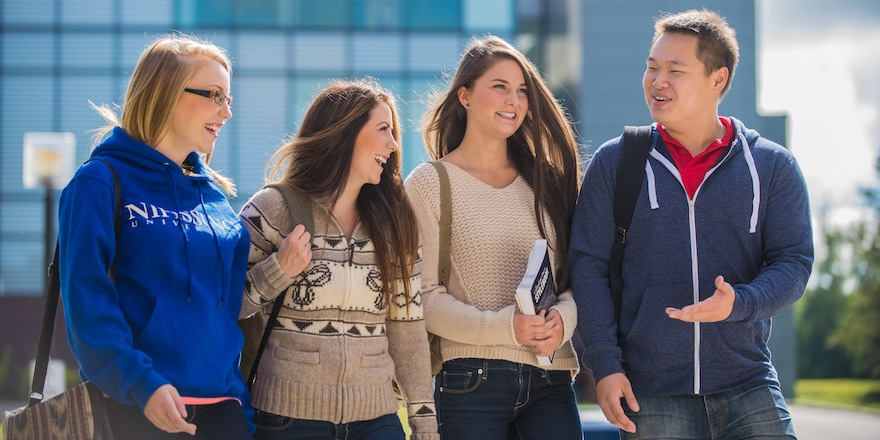 A smiling group of students chats outside Nipissing University.