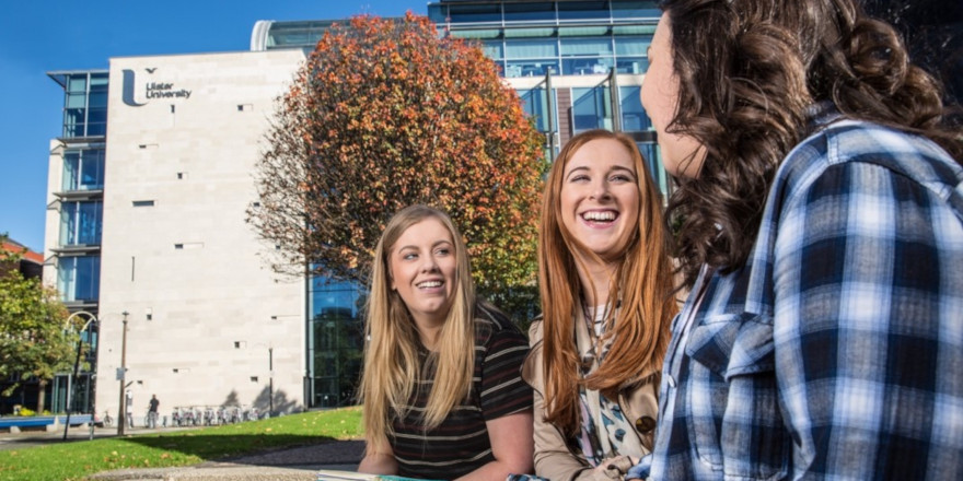 Three students enjoy time together on the sunny Ulster University campus.